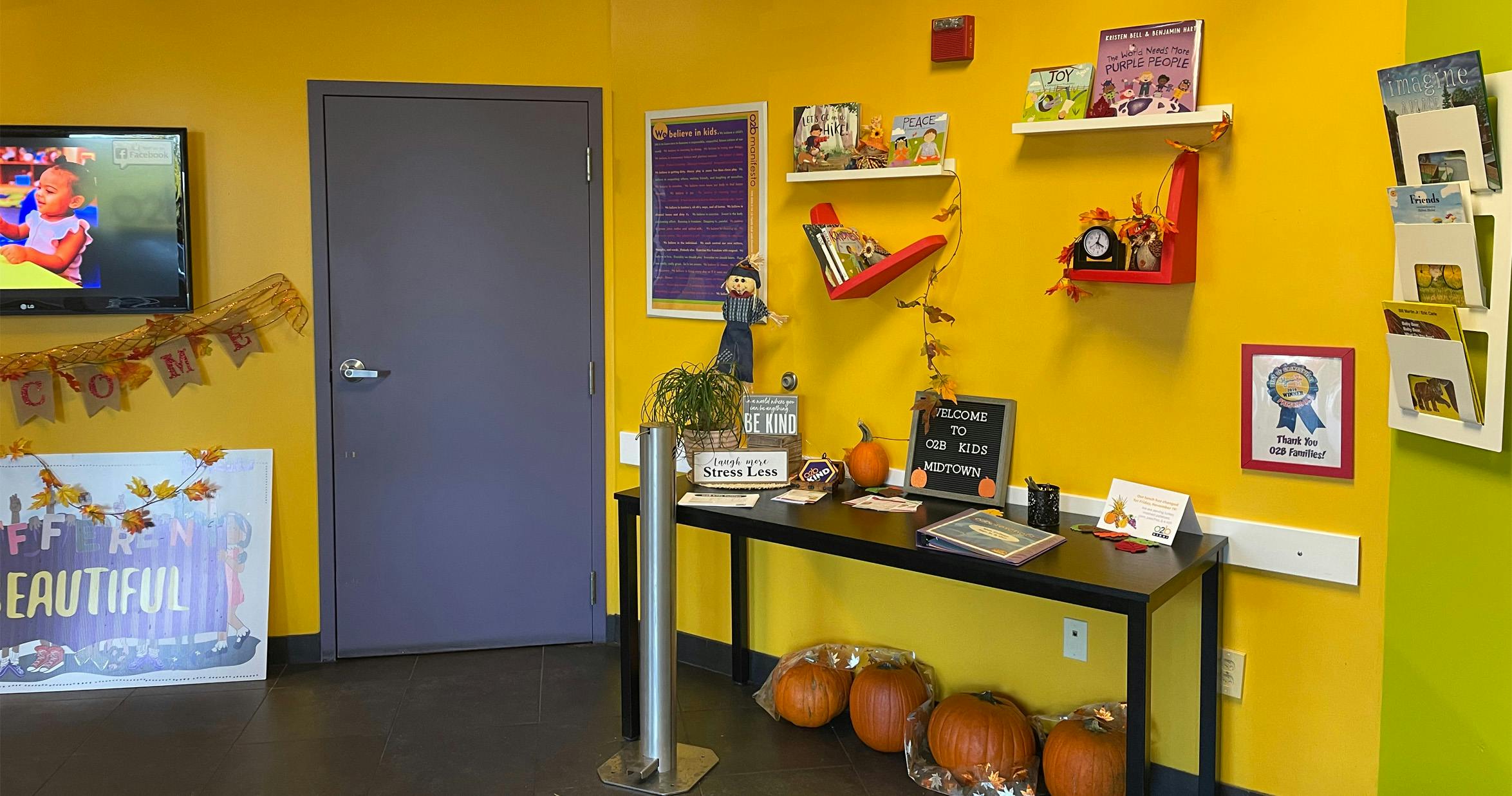 A hallway decorated in autumn theme with pumpkins, fall leaves, and children's books