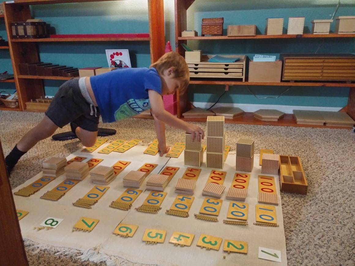 Child on floor arranging wooden blocks and number tiles