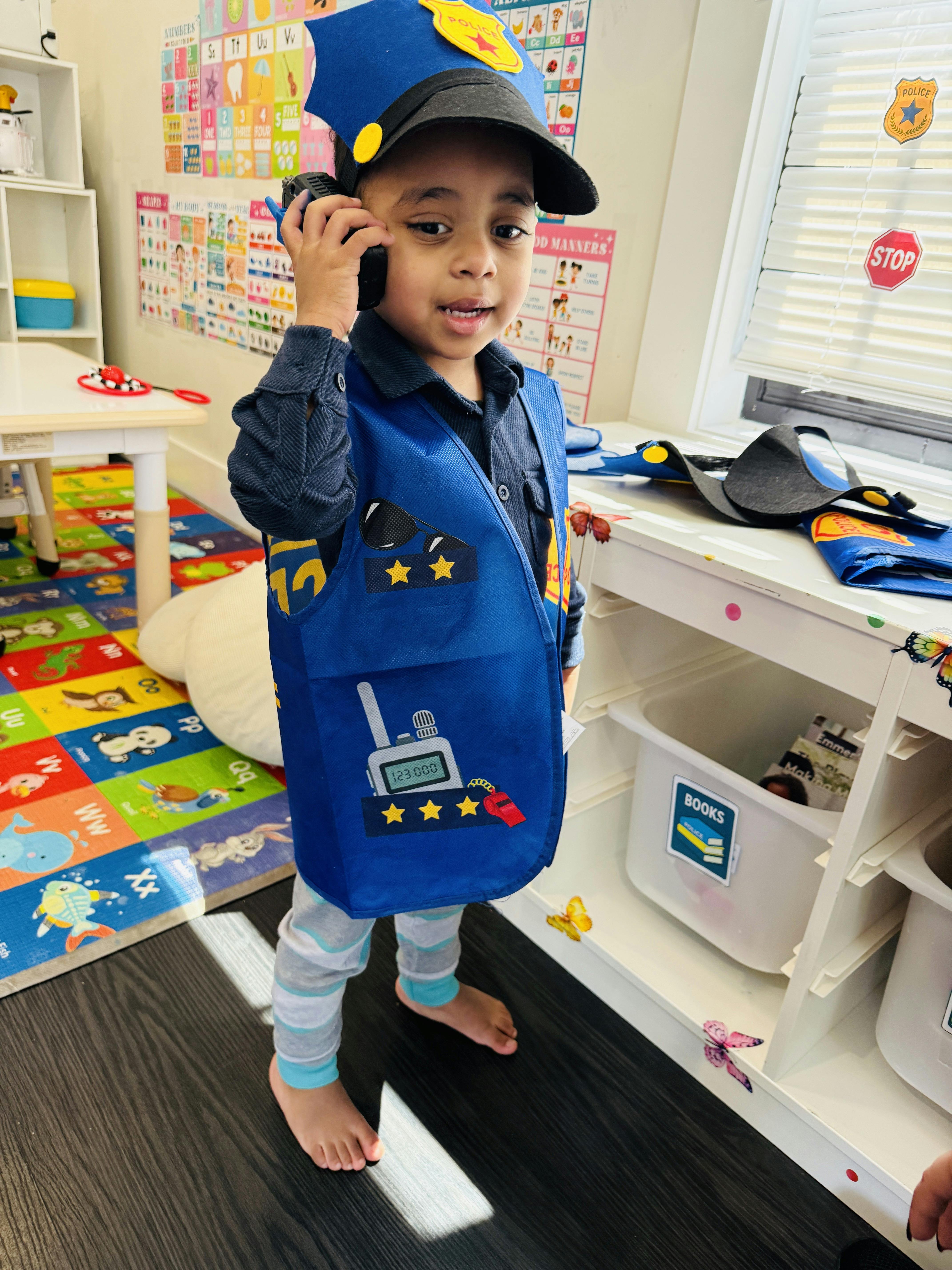 Child wearing a police costume and talking on a toy walkie-talkie