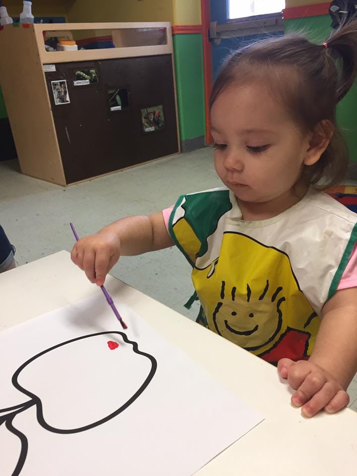 Child painting on paper in a classroom