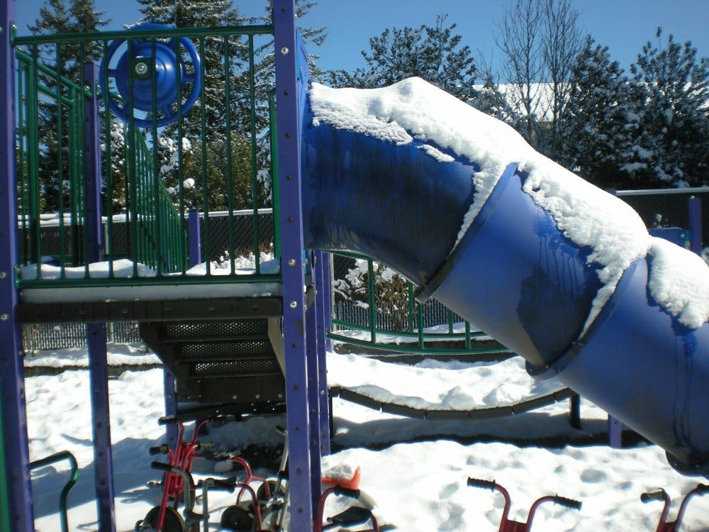 Snow-covered playground slide and climbing structure