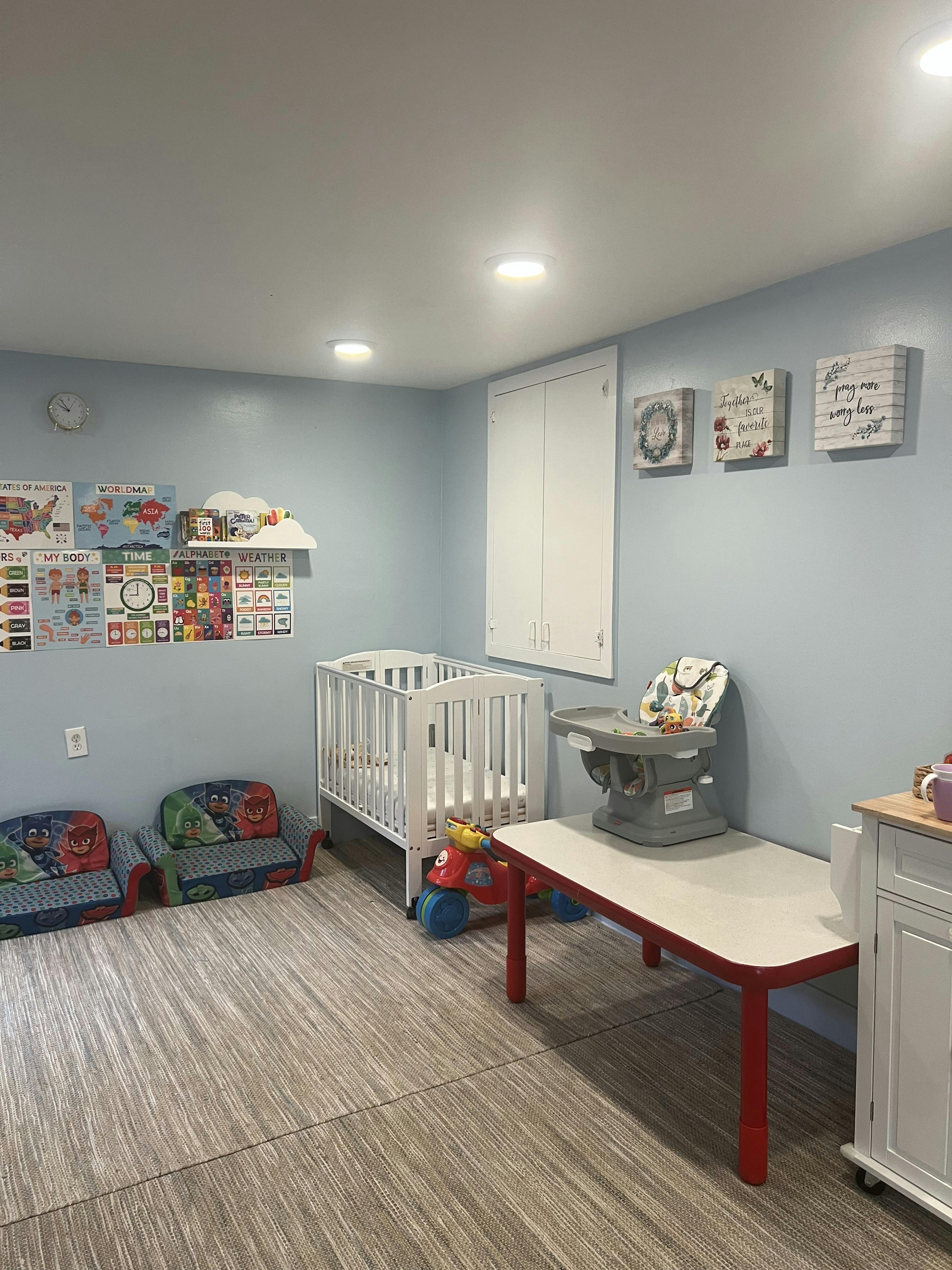 Nursery room with a crib, high chair, small table, and children's chairs