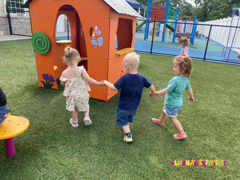 Three children holding hands and walking on a playground