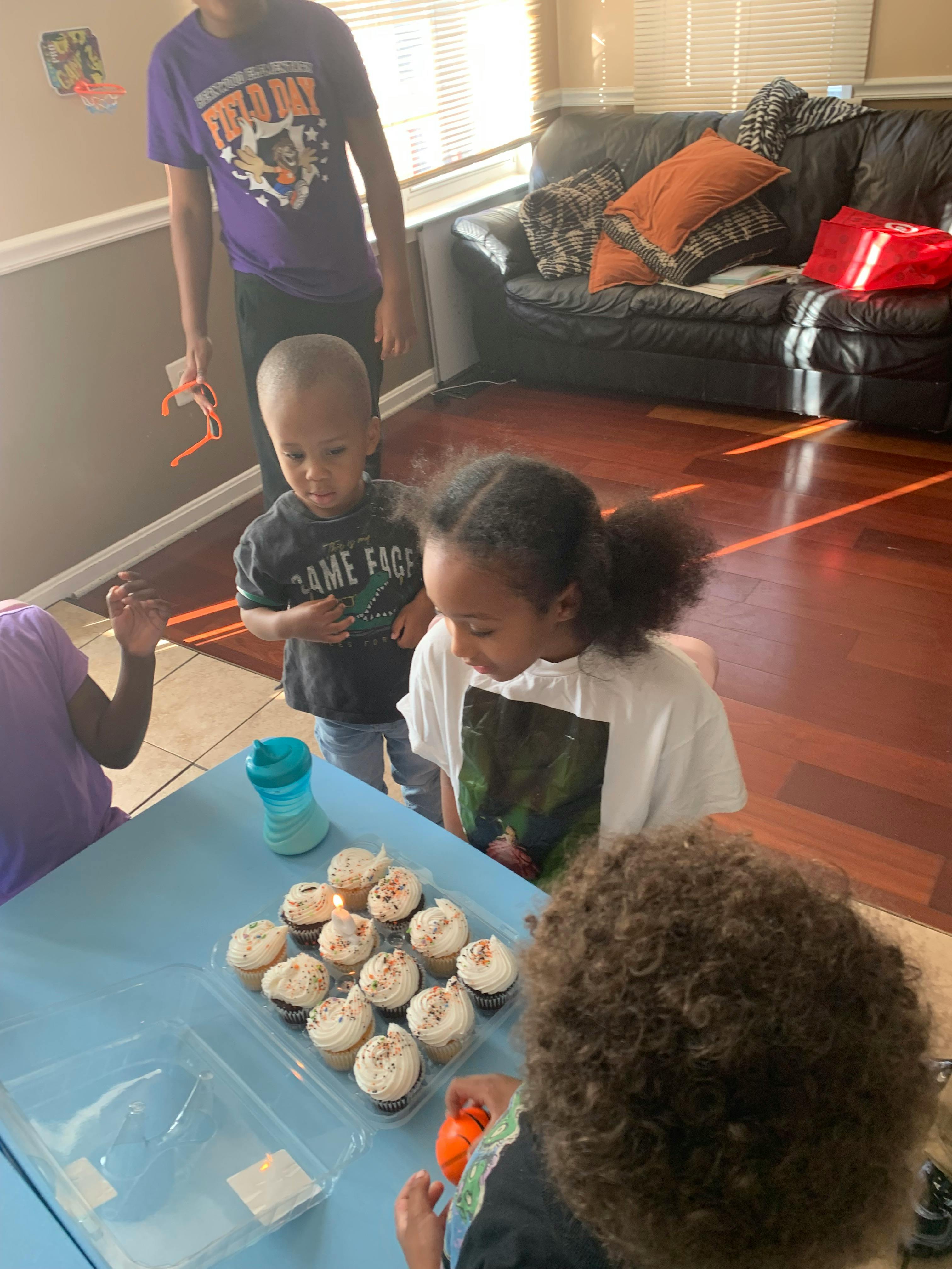 Children gathered around a table with cupcakes