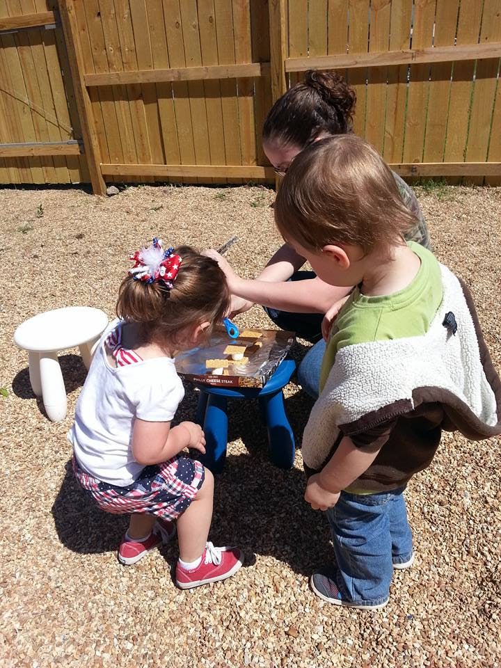 Adult and two children playing with toys outdoors