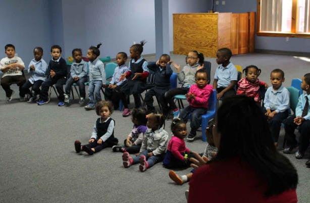 Group of children sitting in a circle, some on chairs and some on the floor