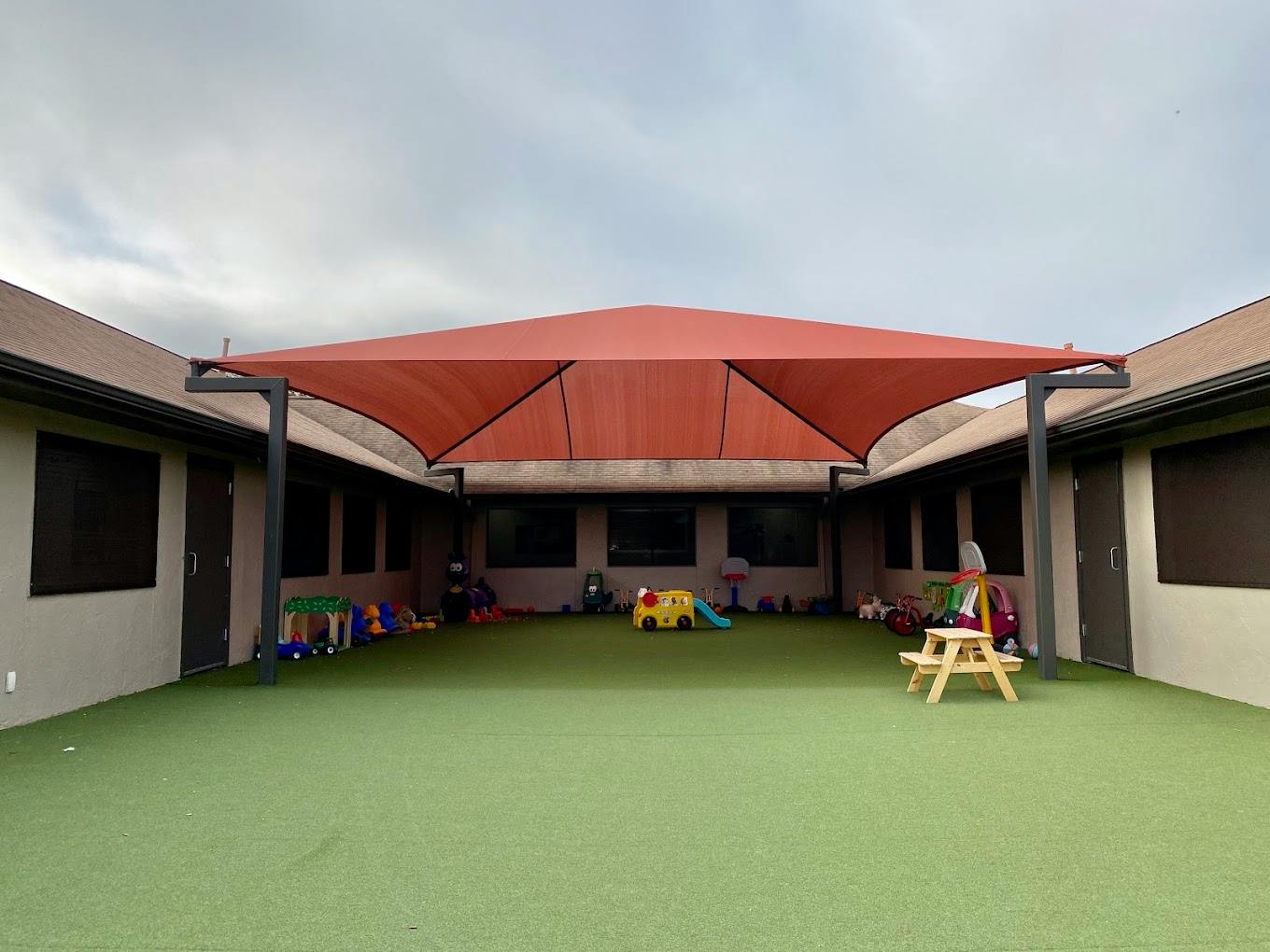Shaded outdoor play area with artificial turf and children's toys