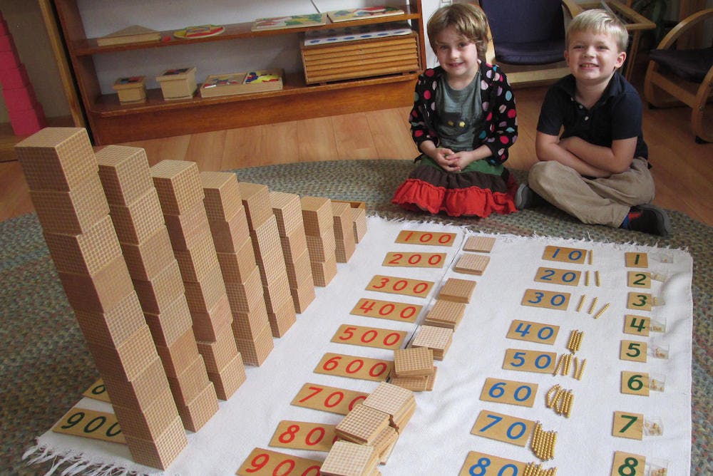 Two children with math materials including wooden blocks and number cards