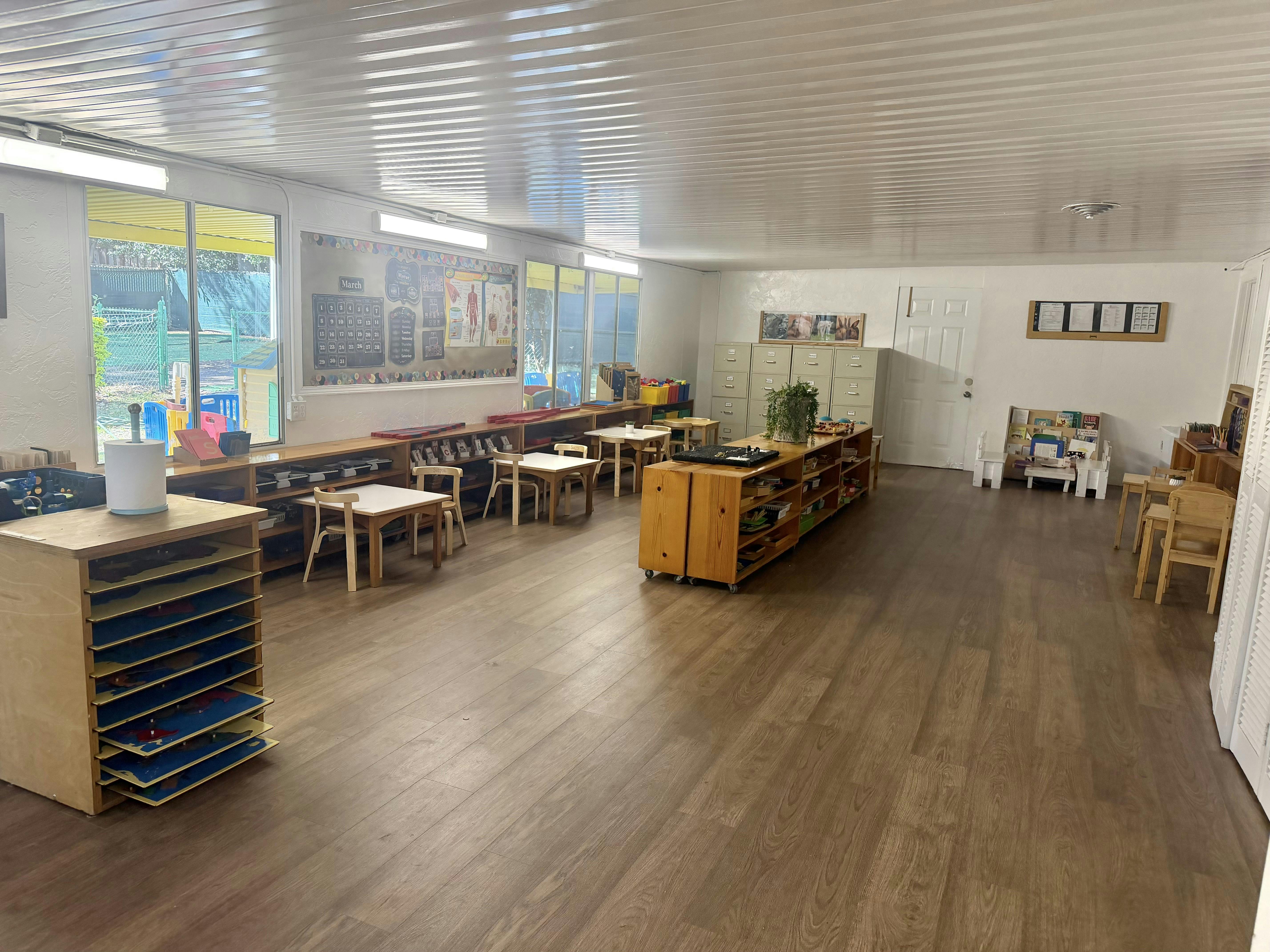 Empty classroom with small wooden tables and chairs