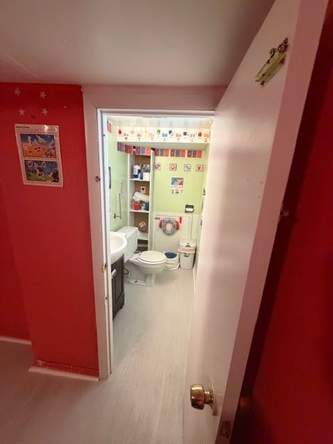 View into a narrow bathroom with a toilet and sink