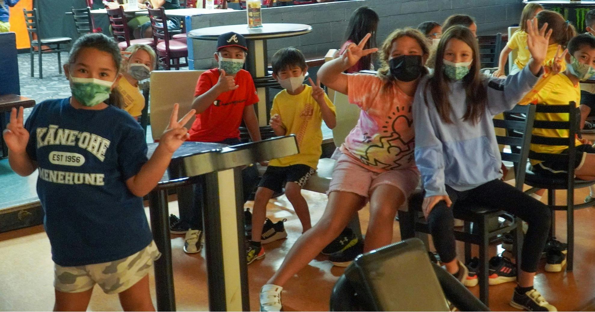 Group of children wearing masks and making peace signs