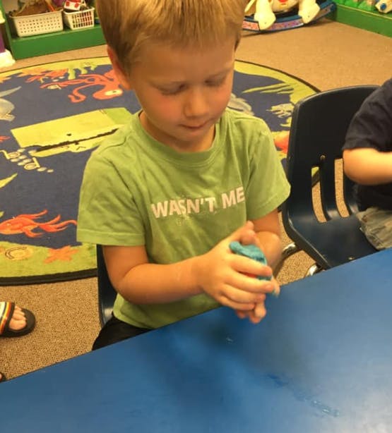 Child playing with modeling clay at a table