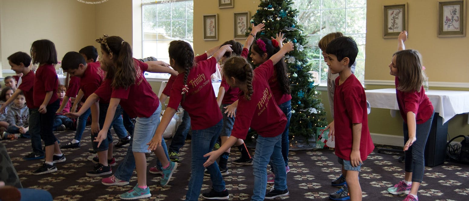 Children in red shirts dancing indoors