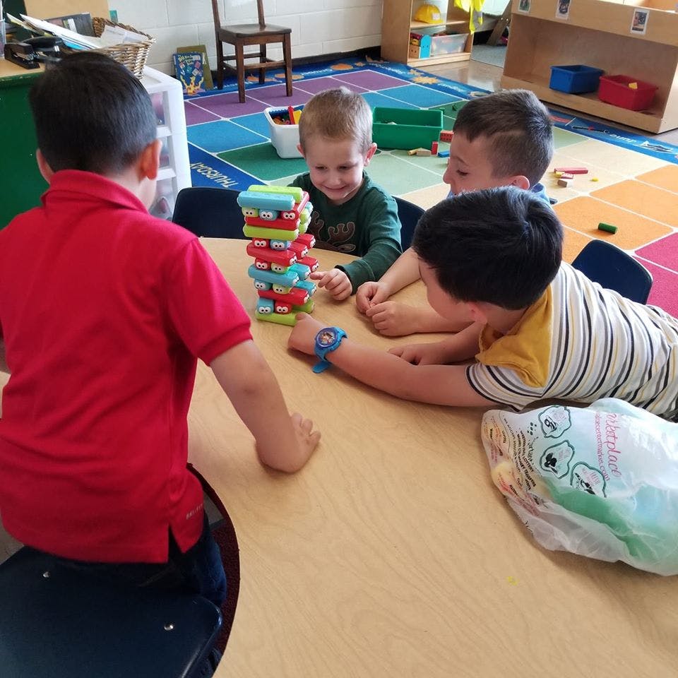 Children playing with a colorful block tower at a table