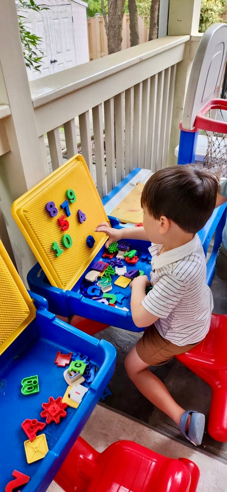 Child playing with magnetic letters and numbers on a yellow board