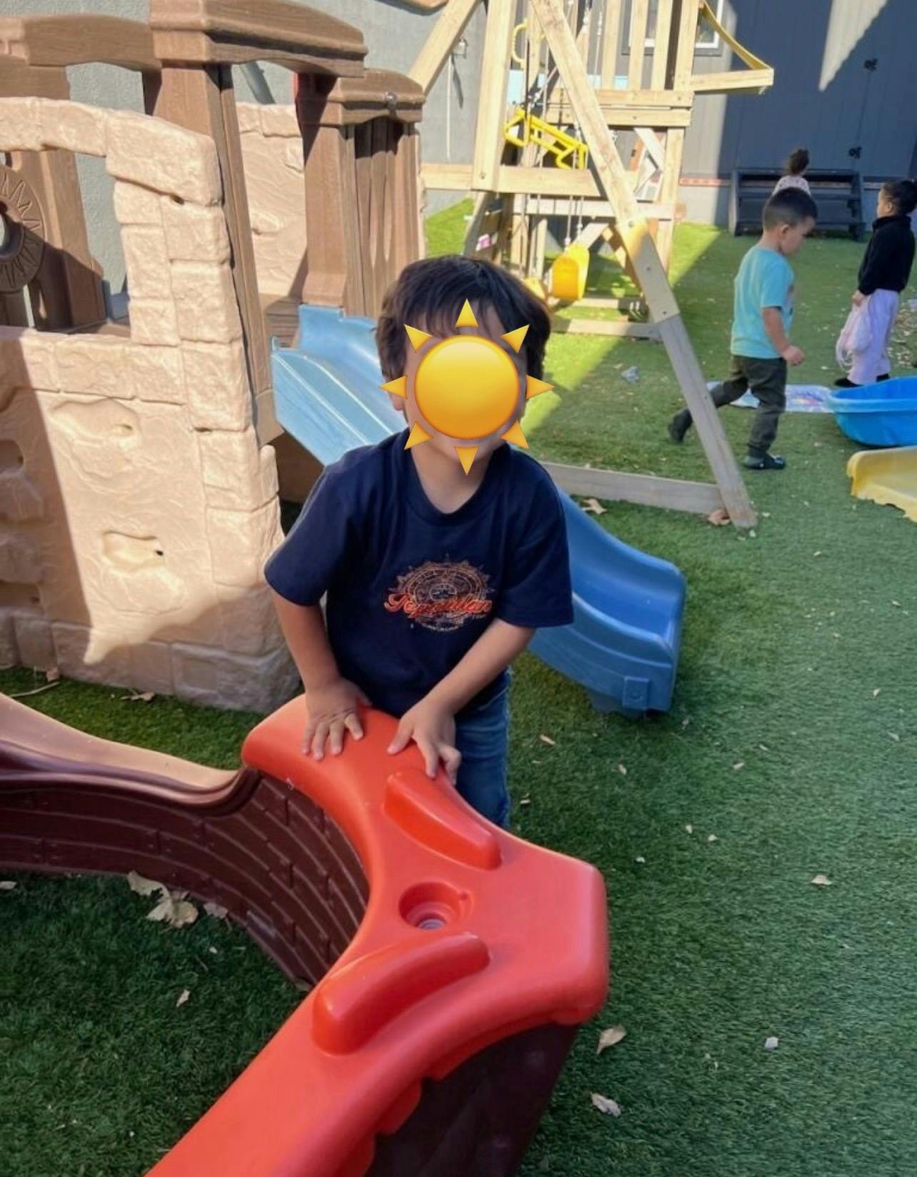 Child standing on a red slide on a playground