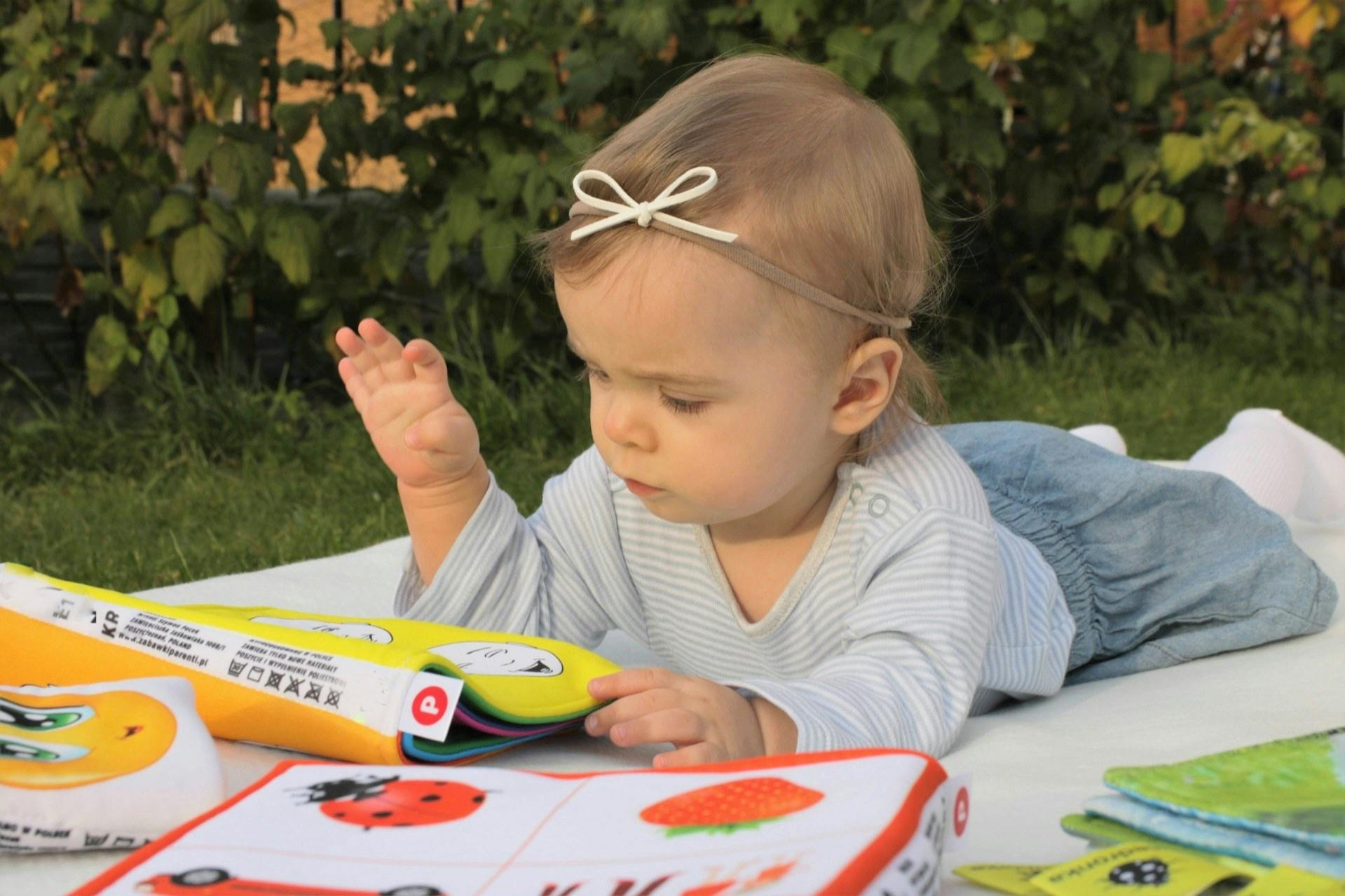 Child on stomach looking at a soft book