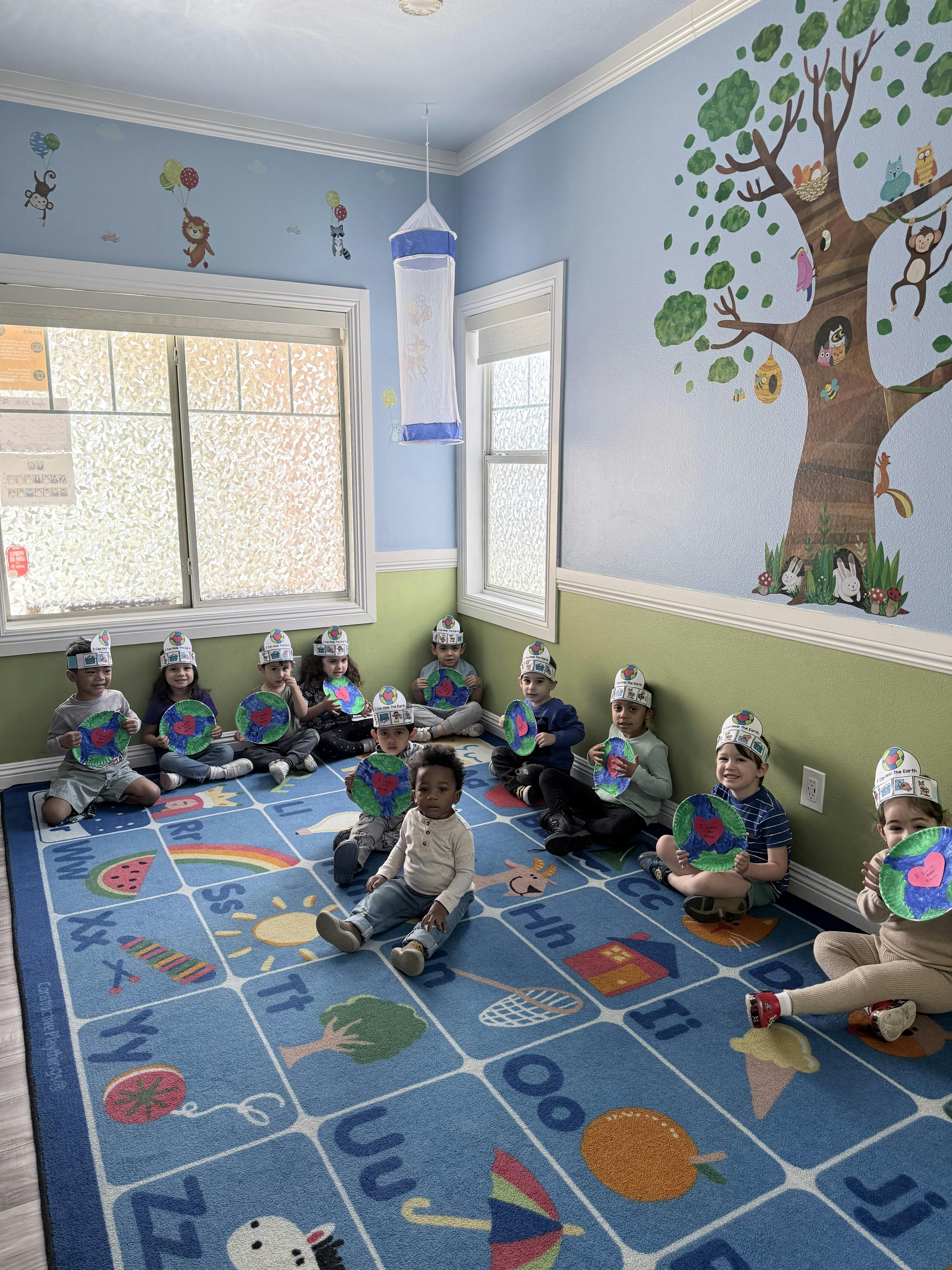 Group of children sitting on a patterned rug holding paper crafts