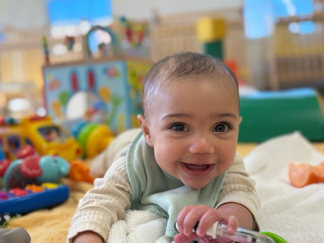 Child on stomach looking forward with toys in background