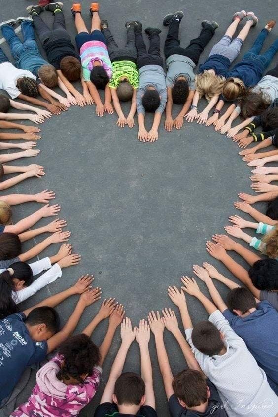 Children lying on the ground in a heart shape