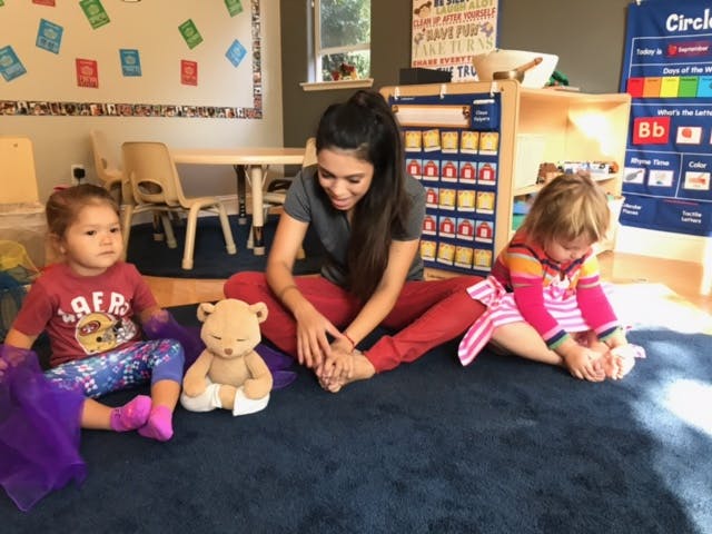 Person and two children sitting on floor in classroom