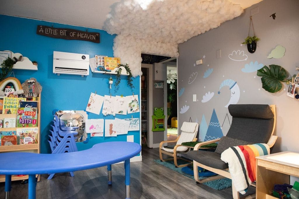 Children's room with blue table, chairs, bookshelf, and two armchairs