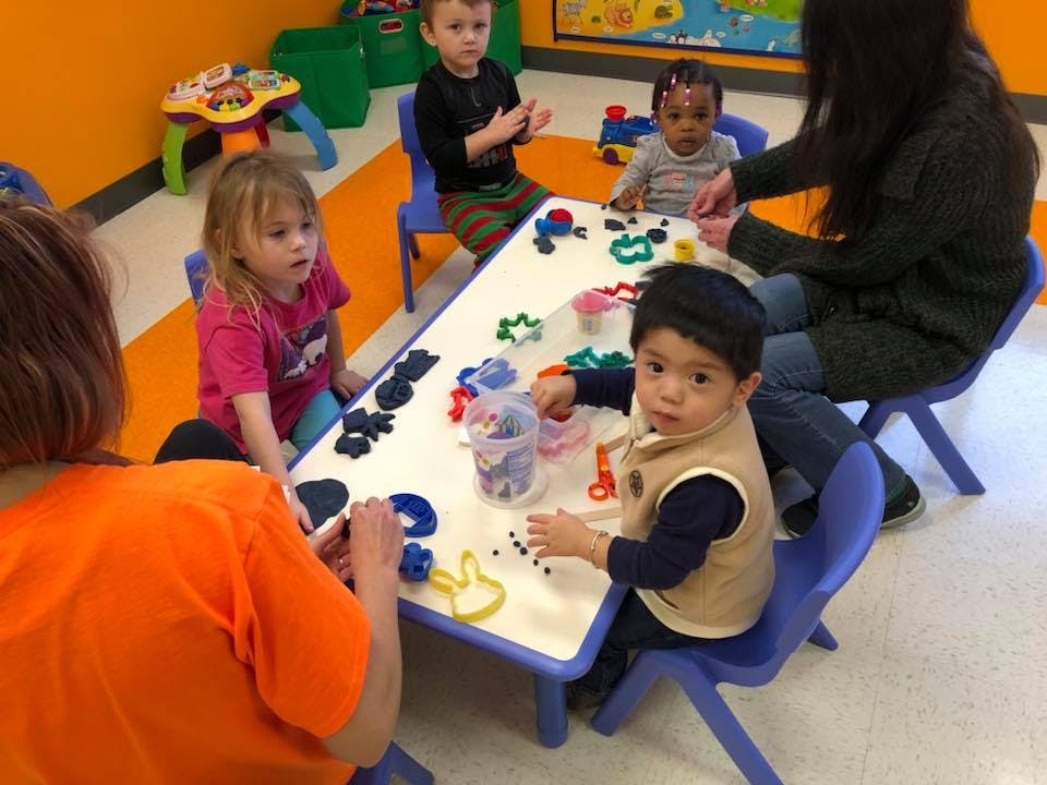 Adults and children at a table with playdough and cookie cutters