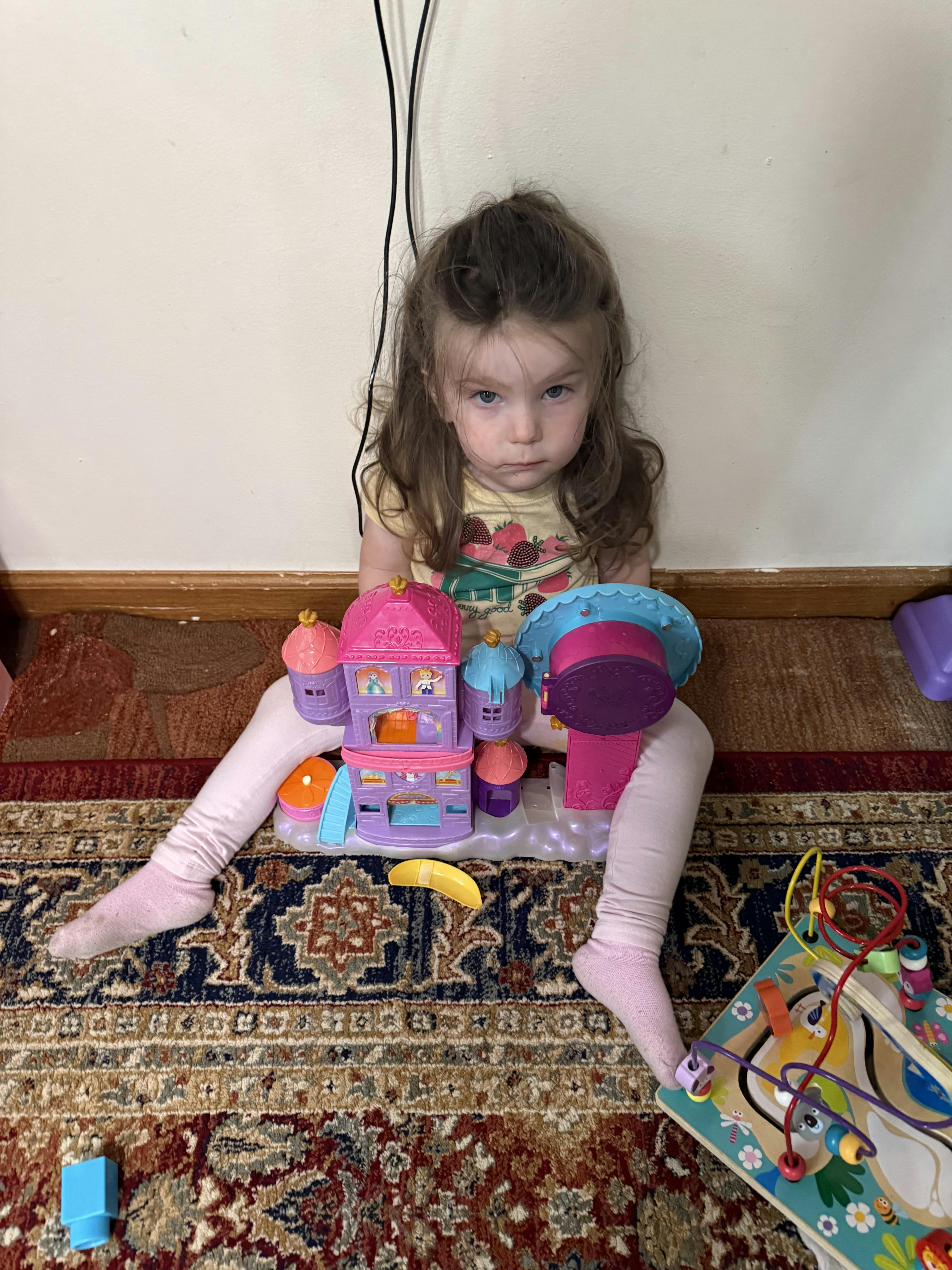 Child sitting on a rug with toys
