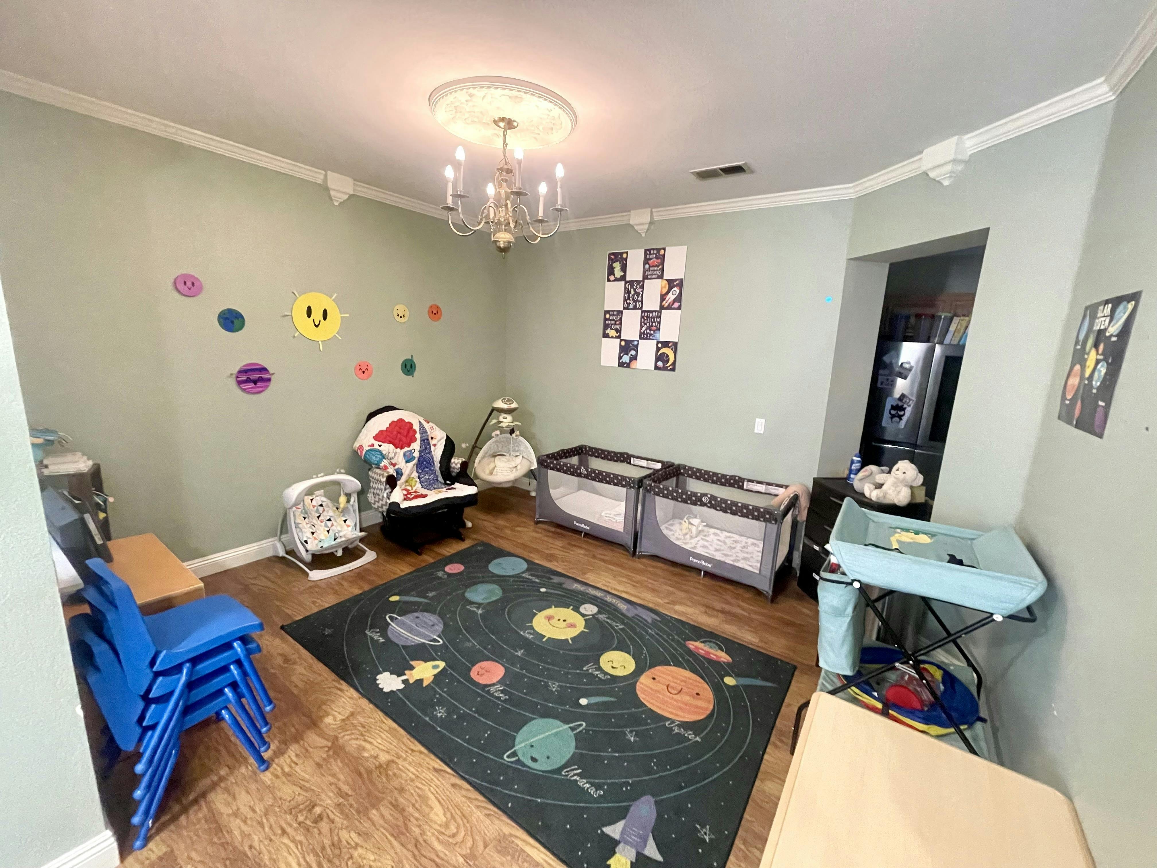 Nursery room with two cribs, a changing table, and a planet-themed rug