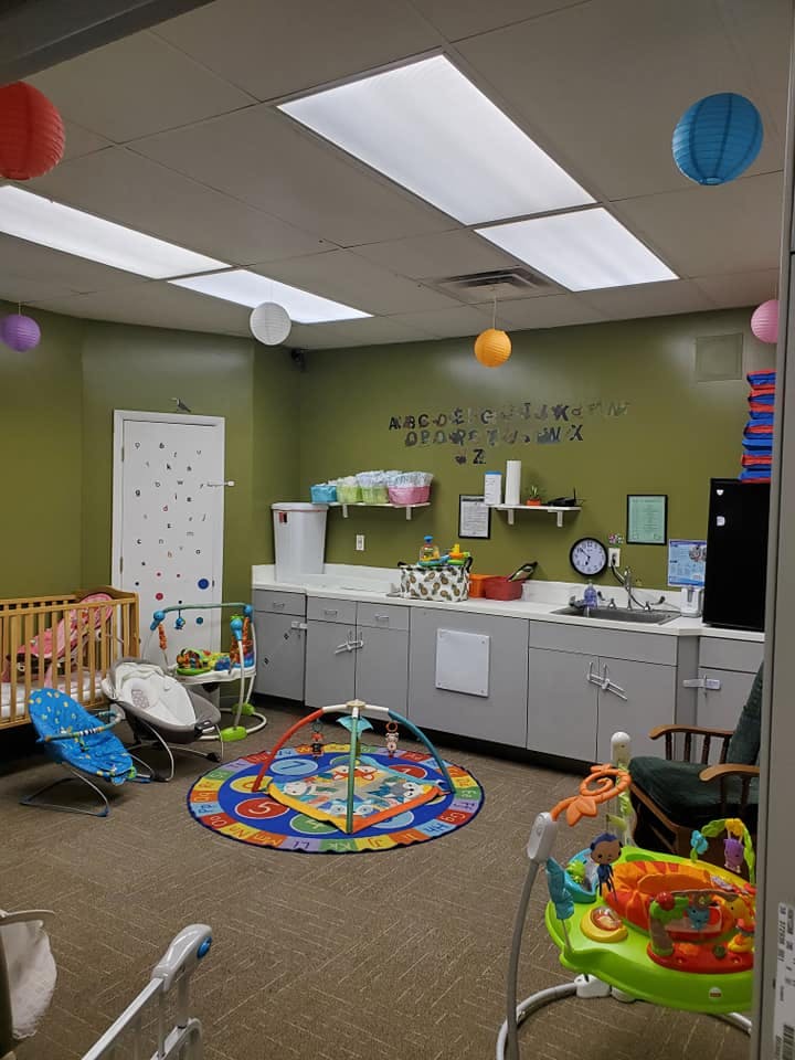 Nursery room with crib, playmat, and baby swings