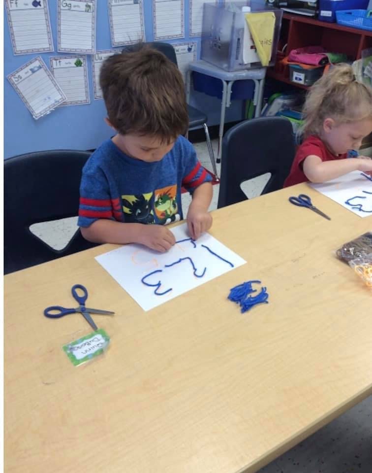Child tracing numbers on paper at a table