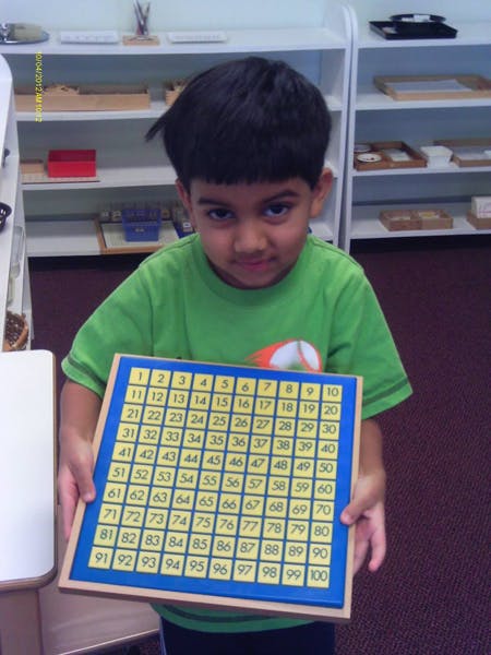 Child holding a number board with numbers 1 to 100