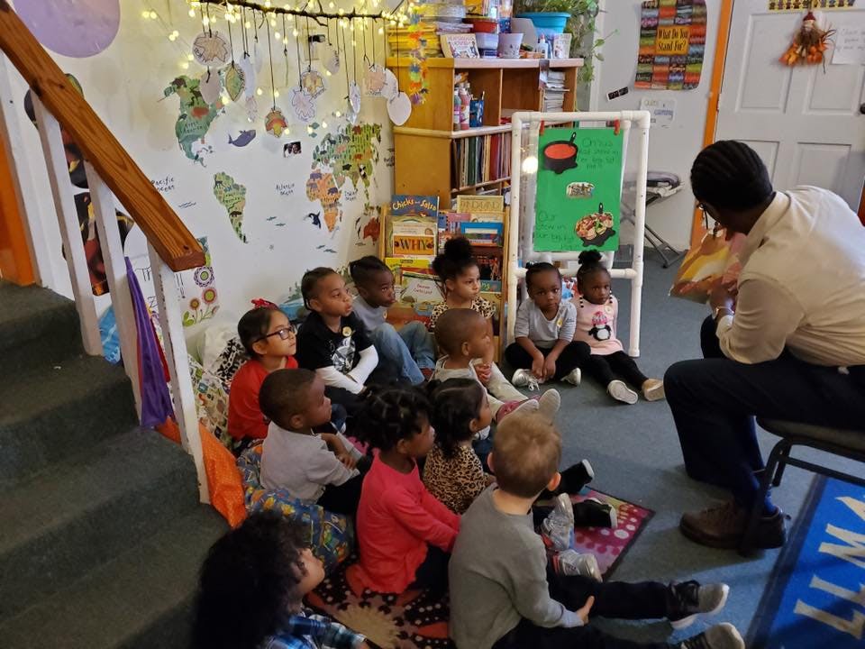 Person reading to a group of children in a classroom