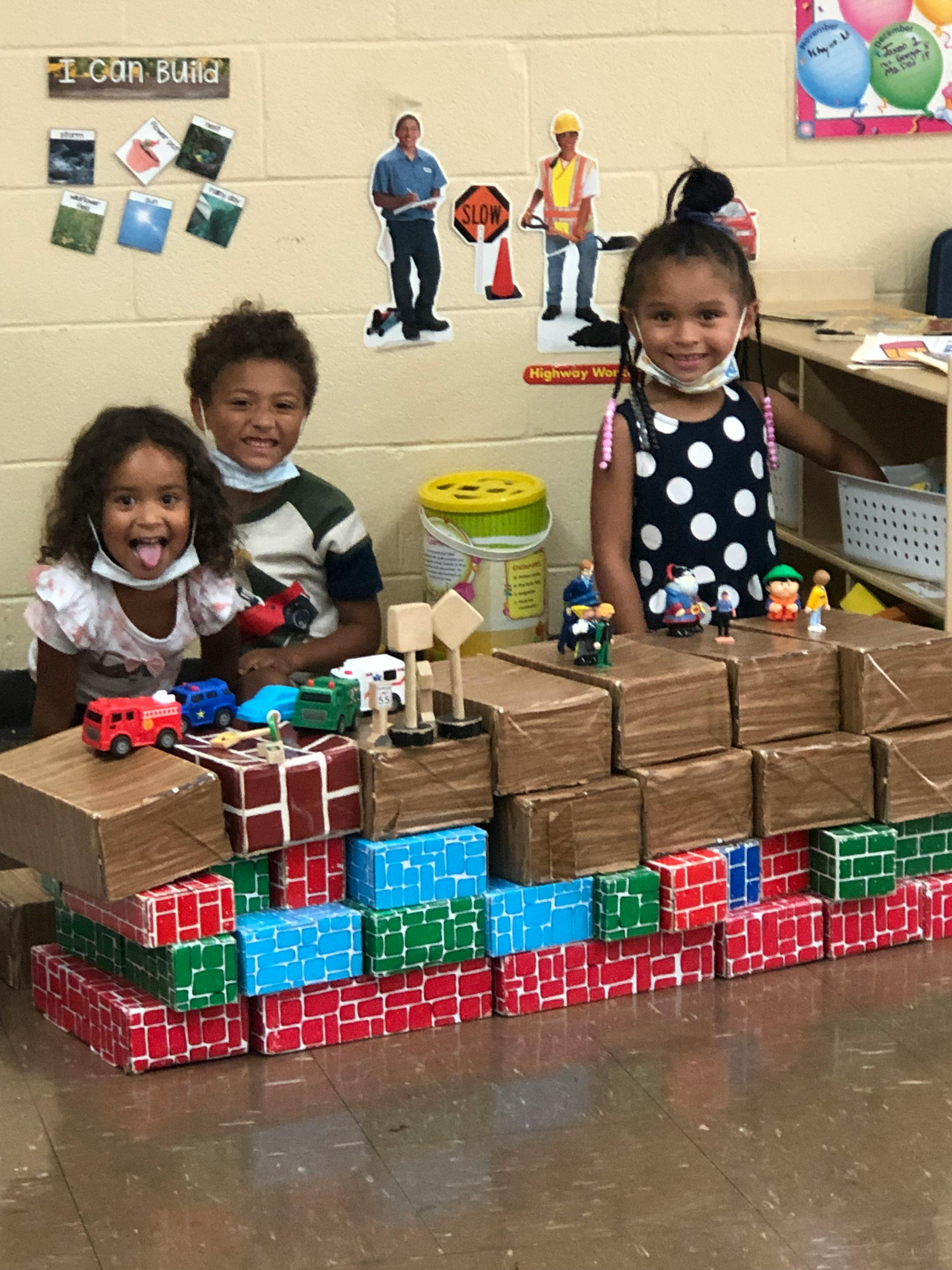 Three children with toy cars and blocks