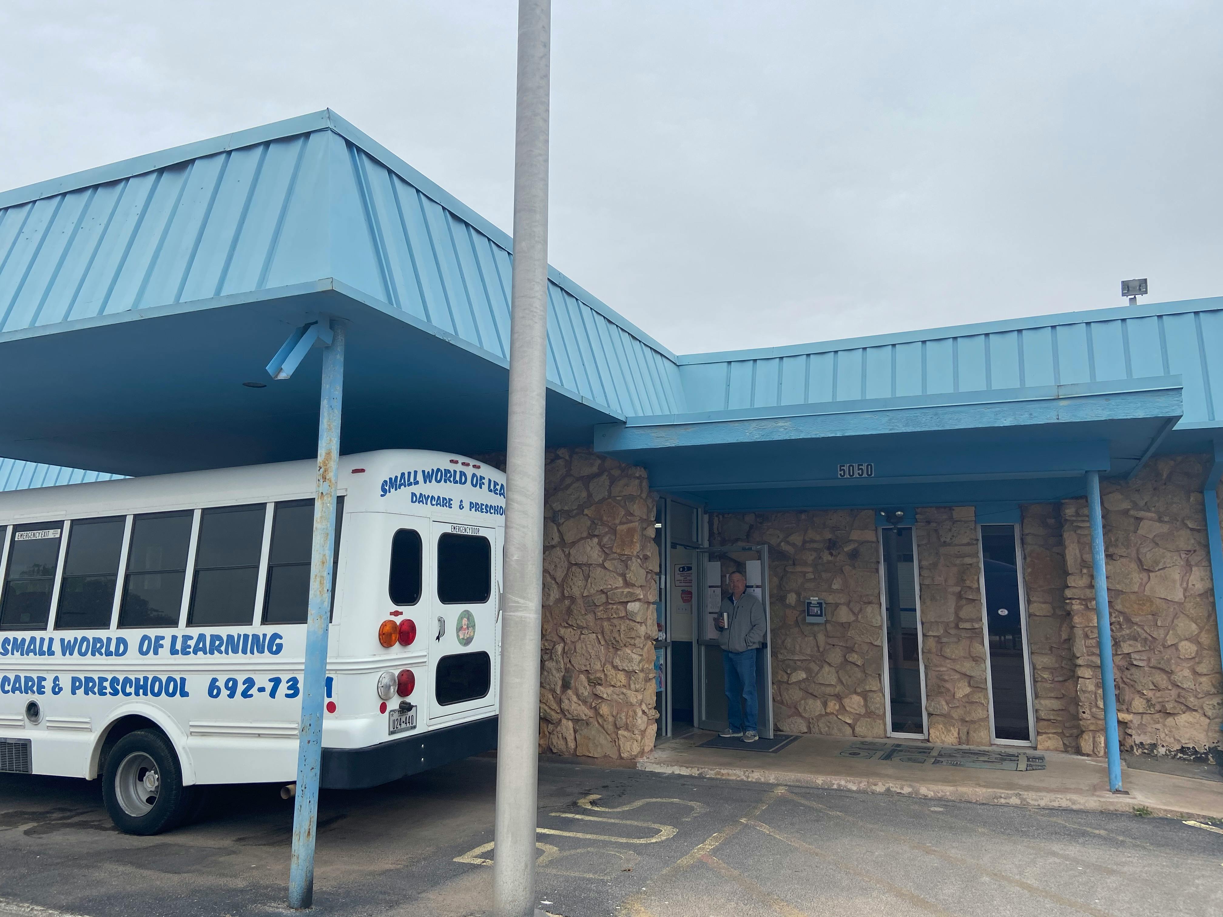 White bus parked under a blue awning next to a building entrance