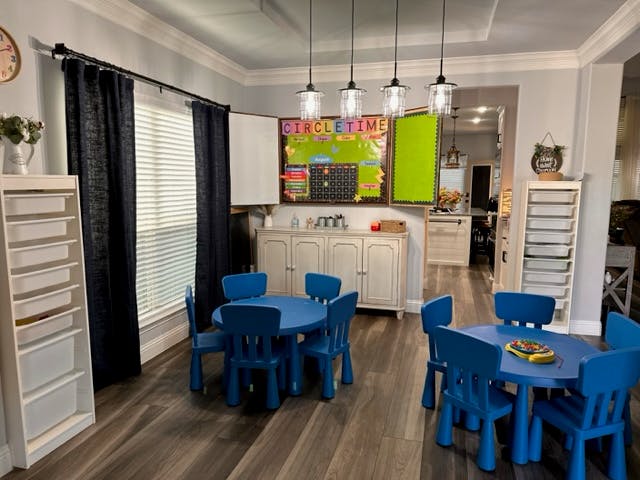 Two blue tables with chairs in a room with a bulletin board
