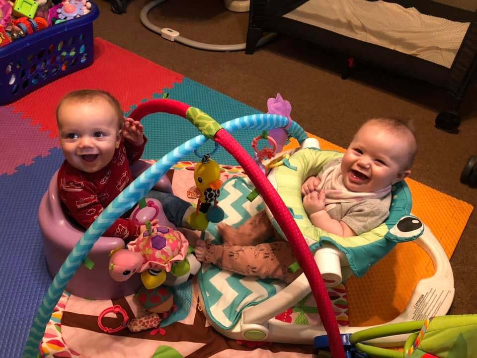 Two children playing with toys on a colorful mat