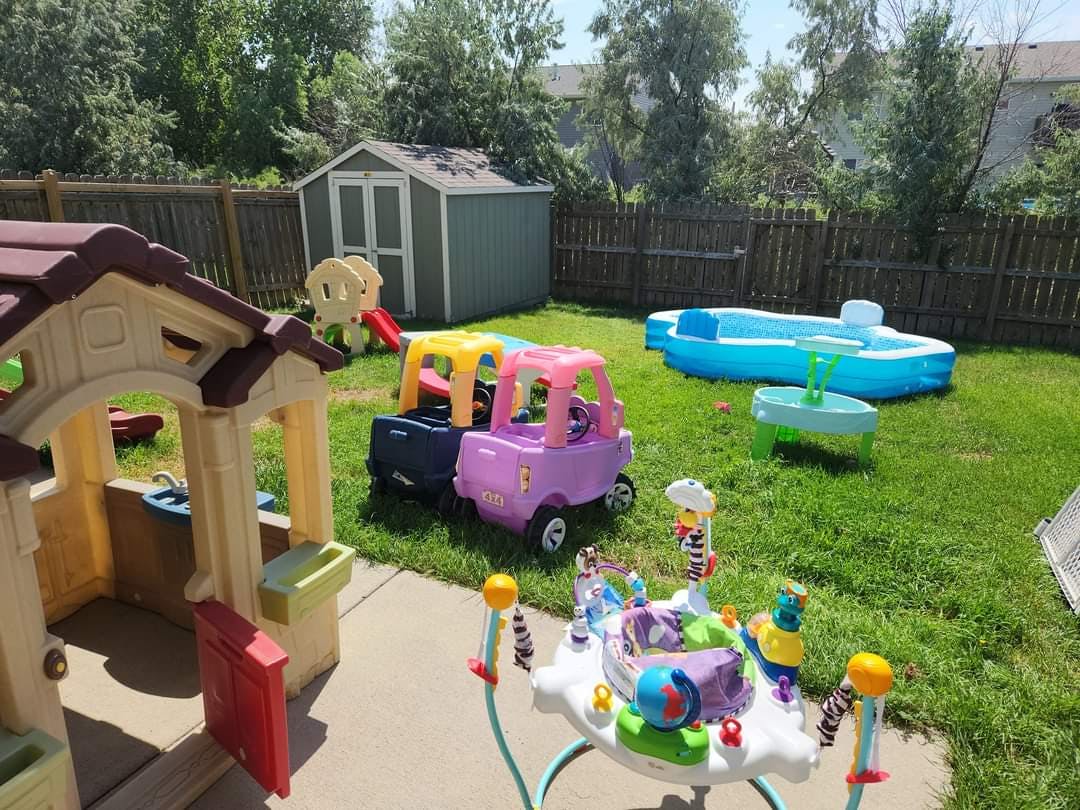 Backyard with children's playhouse, toy cars, and inflatable pool