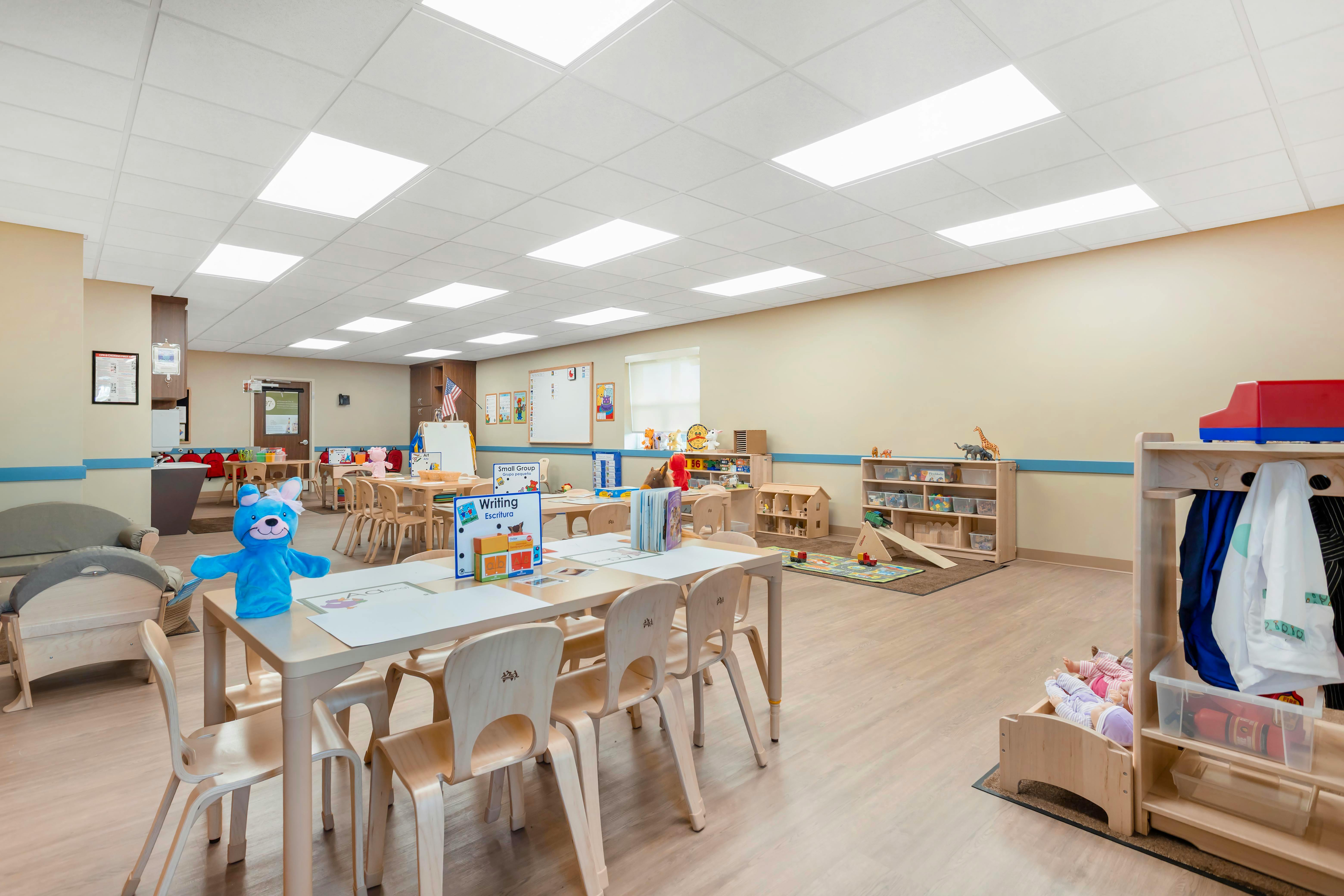 Classroom with child-sized tables and chairs, toys, and educational posters