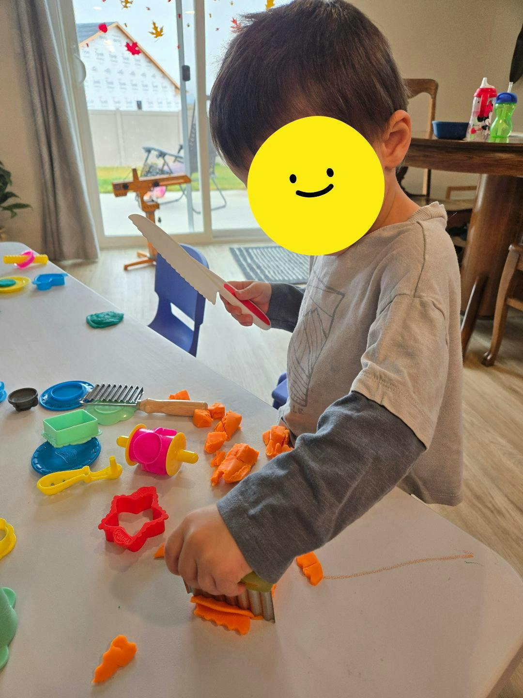 Child playing with orange playdough and tools