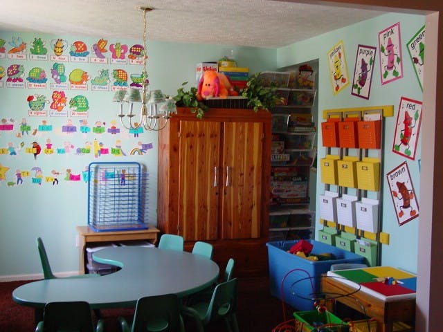 Classroom with small tables and chairs, colorful wall decorations, and storage