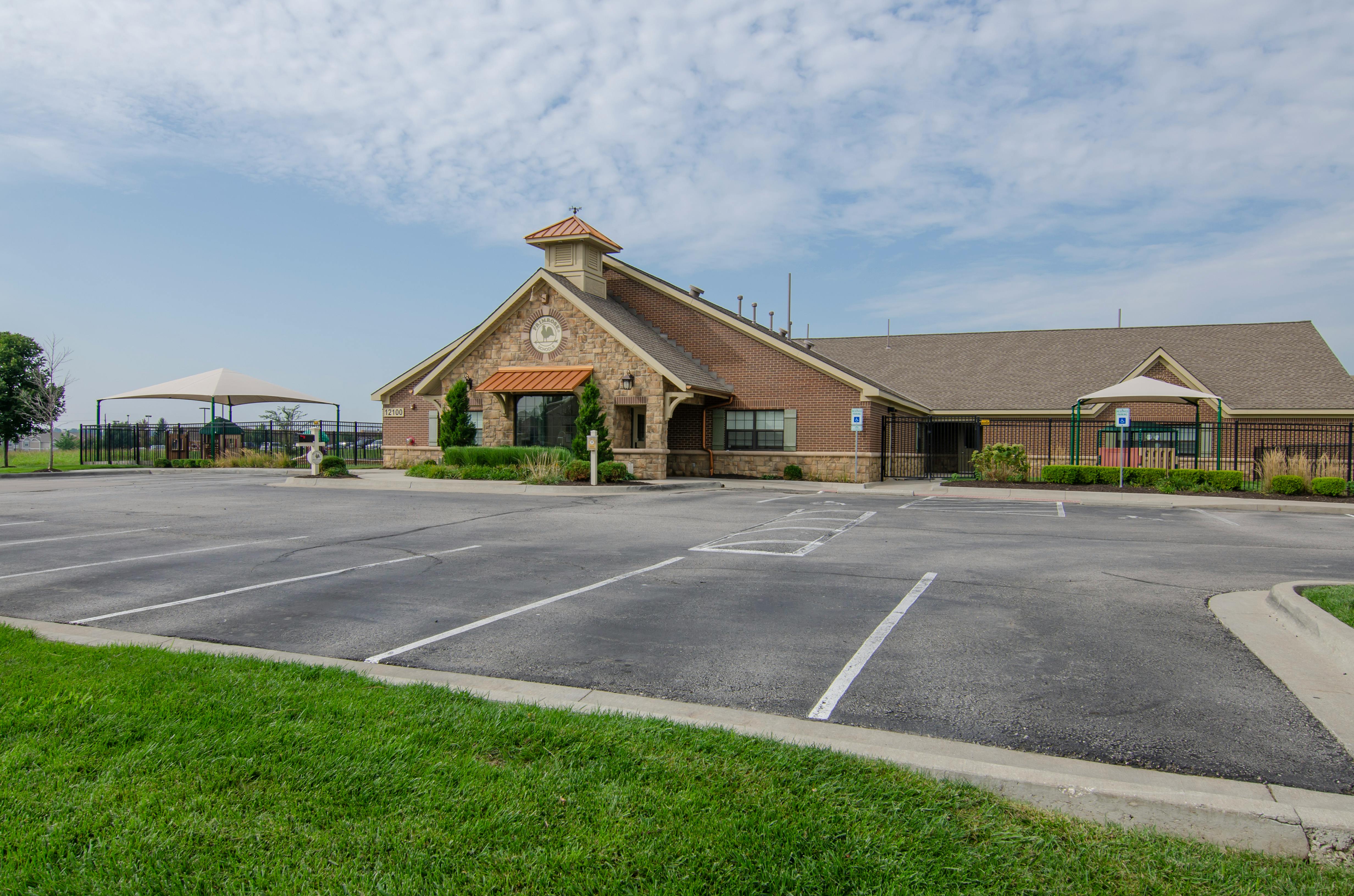 Brick and stone building with a small steeple and a parking lot in front