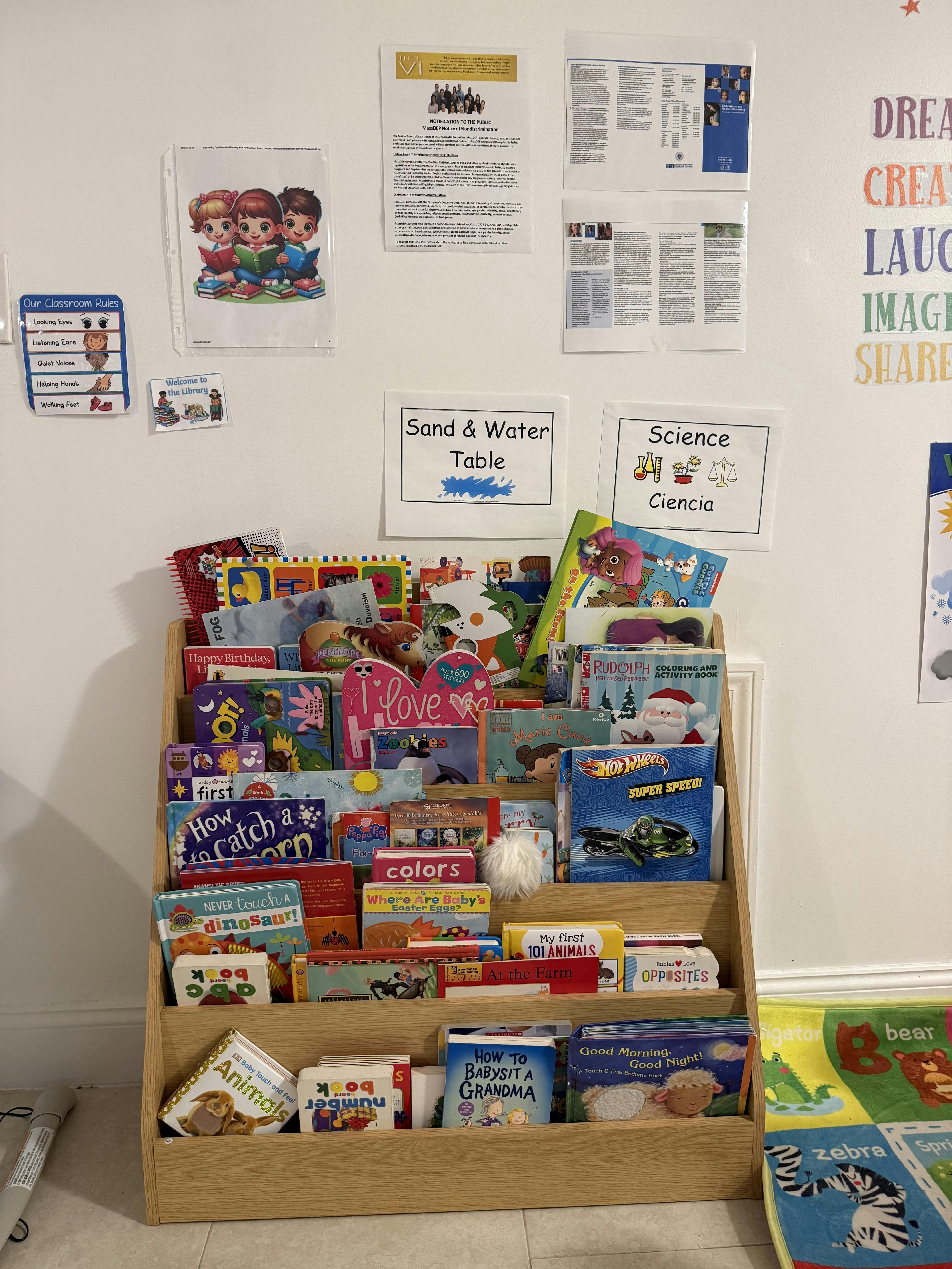A wooden book display filled with various children's books and educational posters on the wall
