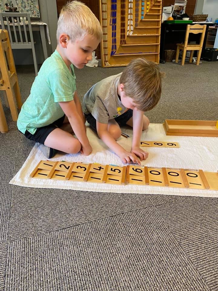Two children playing with number blocks on a mat