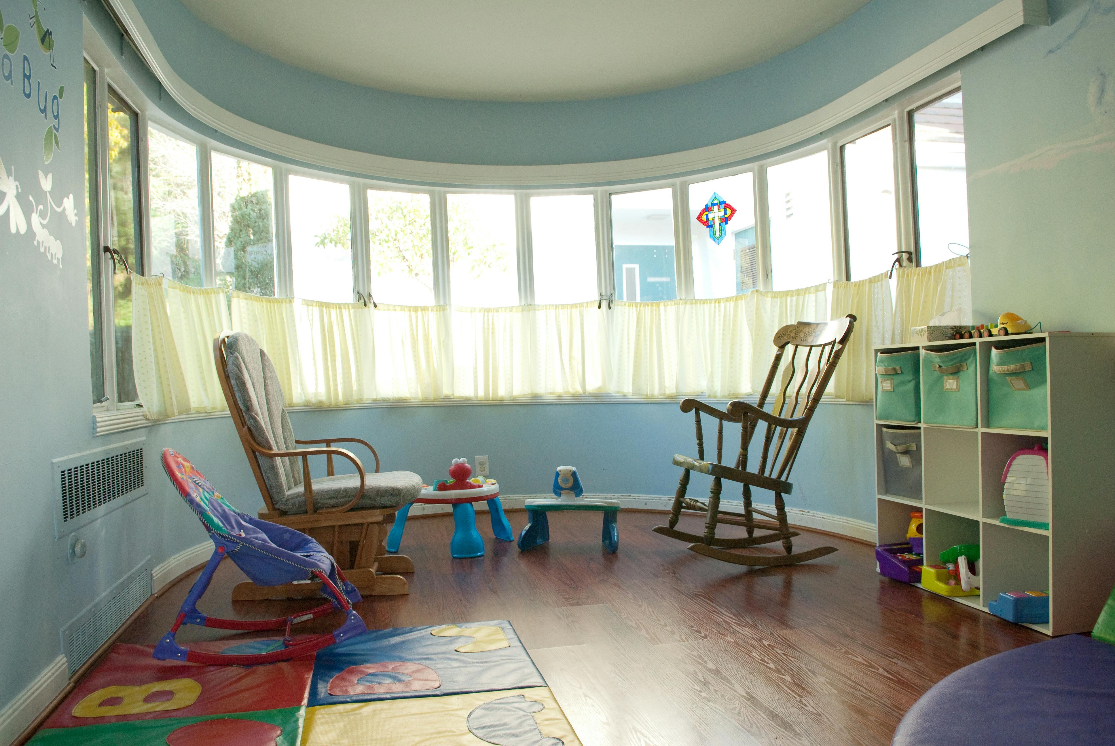 Nursery room with two rocking chairs, a baby bouncer, and a toy shelf