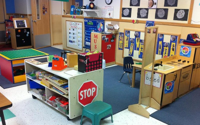 An empty classroom with play areas, including a toy kitchen and building block table