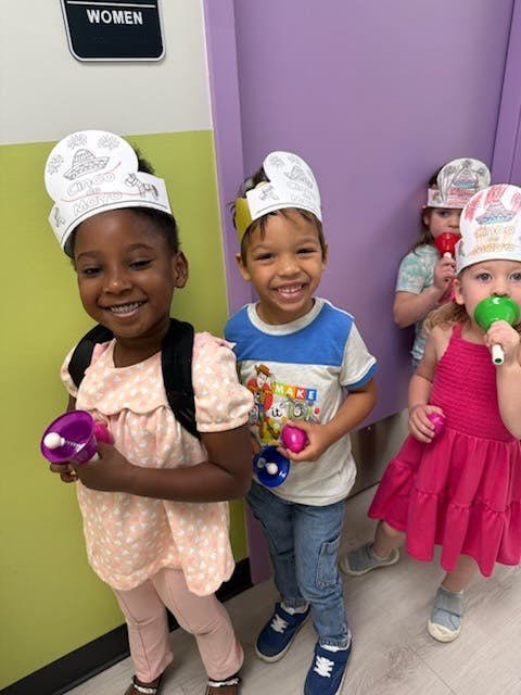 Children wearing paper crowns and holding shakers