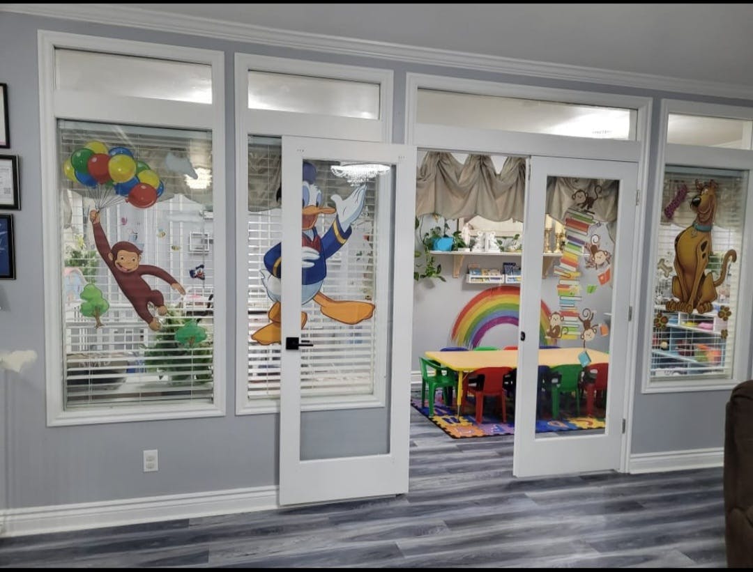 Glass doors and windows with cartoon character decals leading to a colorful playroom