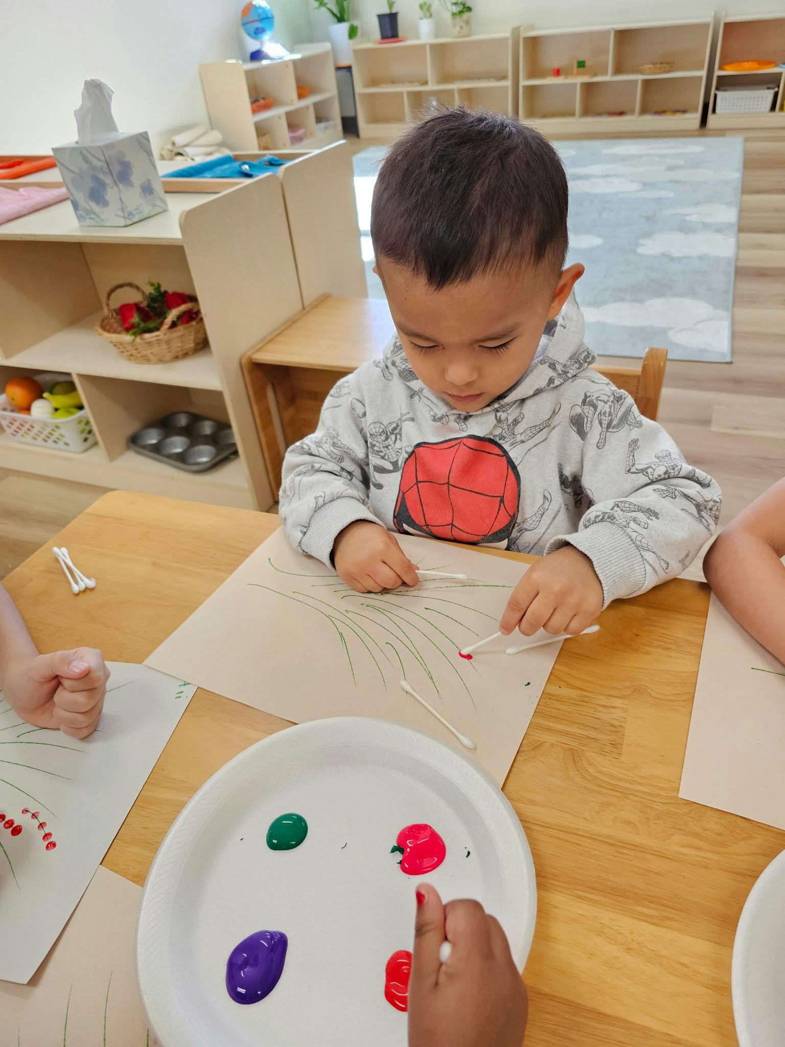 Child painting with cotton swabs in a classroom