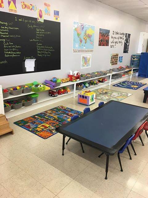 Classroom with a blackboard, shelves of toys, and a table with chairs